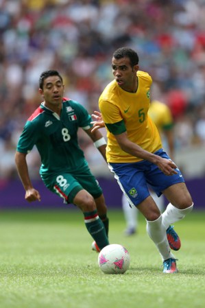 Marco Fabián de México se disputa la bola con Sandro de Brasil.