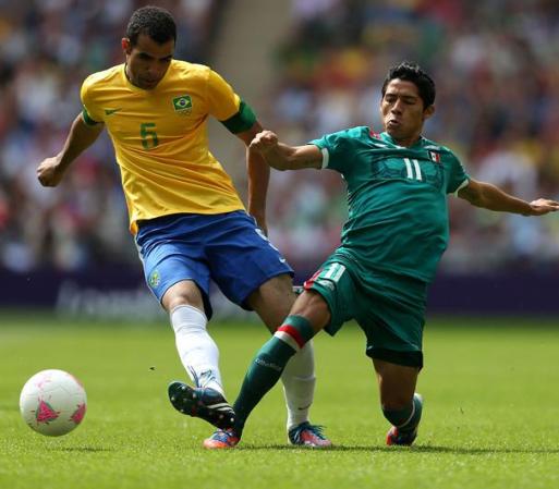 Sandro of Brasil es alcanzado por Javier Aquino de Mexico durante la Final de Futbol de Londres 2012.