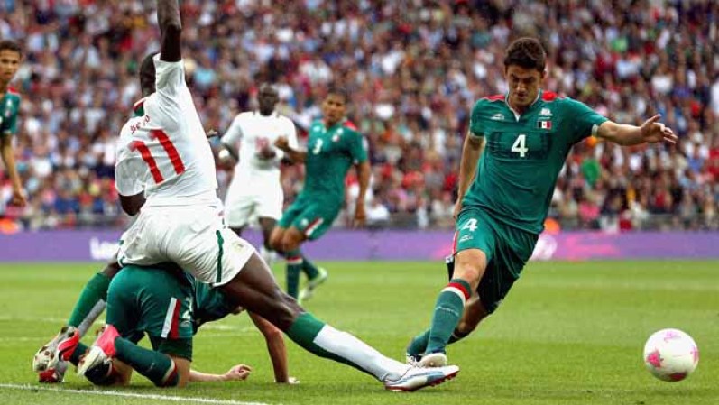 Kalidou Yero, de Senegal, salta sobre Israel Jiménez, de México, y trata de arrebatarle la bola a Hiram Mier, de México.