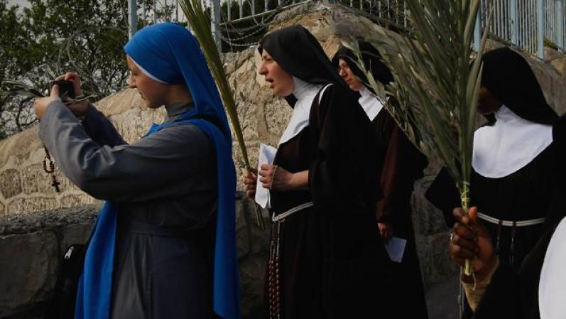 JERUSALEM - APRIL 05: Catholic nuns taking part in the traditional Palm Sunday procession from the Mt. of Olives stop to photograph and react to the view of the Old City on April 5, 2009 in Jerusalem, Israel. The festival, which falls at the start of the Holy Week, commemorates the triumphant entry of Jesus into Jerusalem in the days before his Passion, according to the Gospels of Mark, Matthew, Luke and John. (Photo by David Silverman/Getty Images)