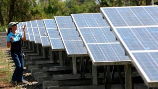 Mujer camina frente a paneles solares