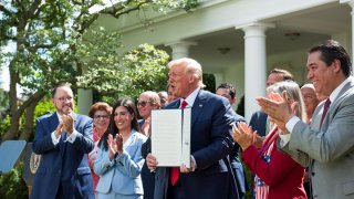 El presidente de EE.UU., Donald J. Trump (c), sostiene la orden ejecutiva con la que crea la Comisión de Asesores para la Prosperidad de los Hispanos, este 9 de julio de 2020, en la Casa Blanca, Washington.