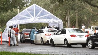 People in cars line up to receive free COVID-19 rapid tests at a drive through site