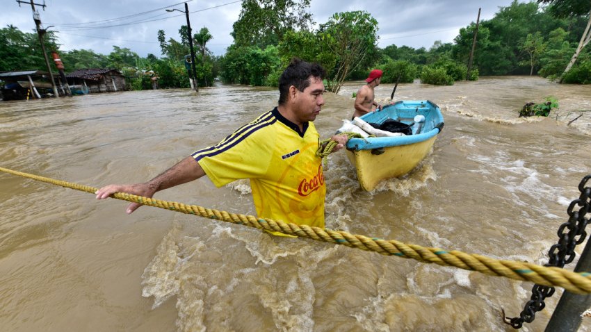 Dos personas cruzan una inundación en Tabasco