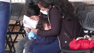 Foto de madre abrazando a sus dos pequeños mientras lee un documento.