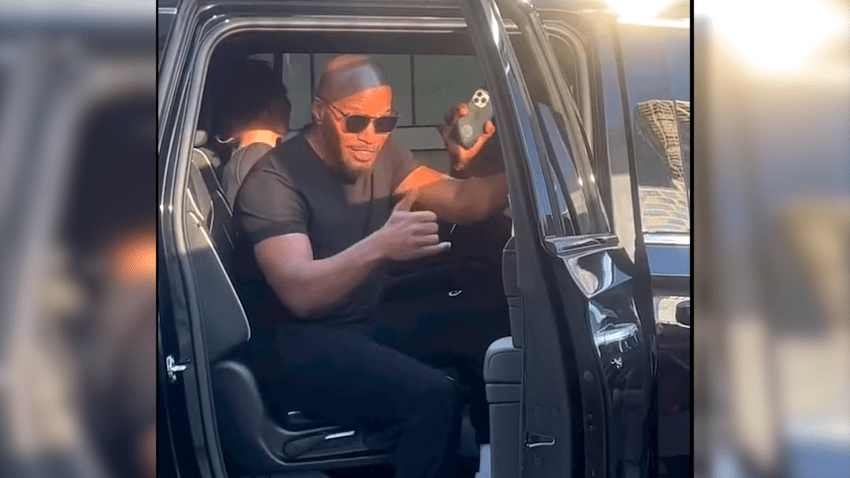 Actor Jamie Foxx waves from a car