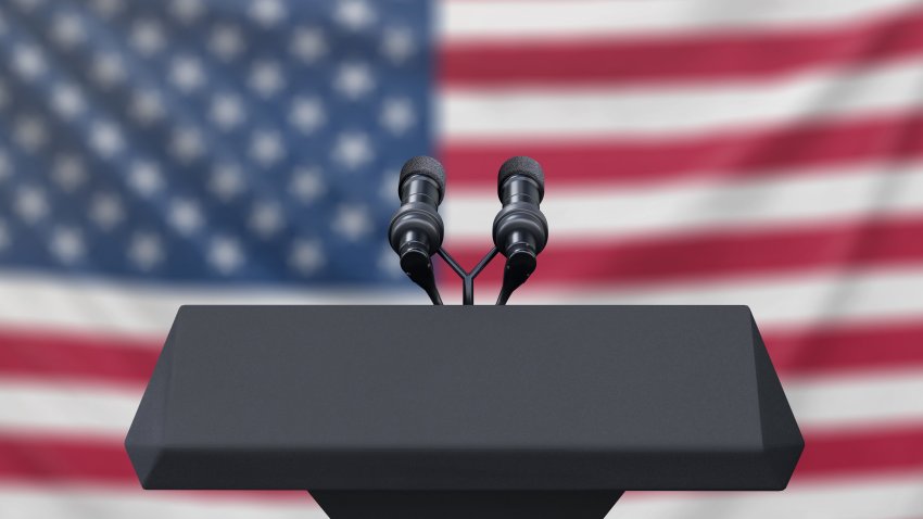 Podium lectern with two microphones and United States flag in baackground