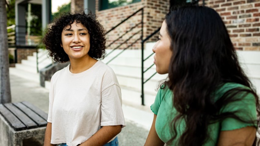 Two young women sitting outdoors and talking