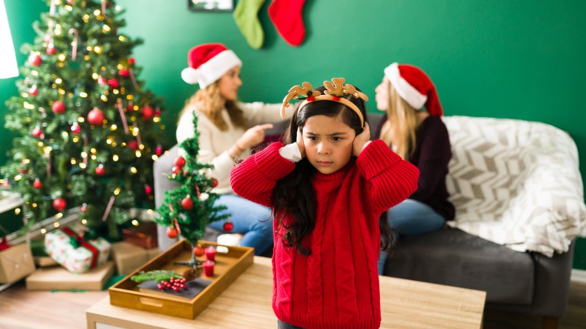 Stop fighting. Sad little girl covering her ears while listening to her angry parents having a discussion