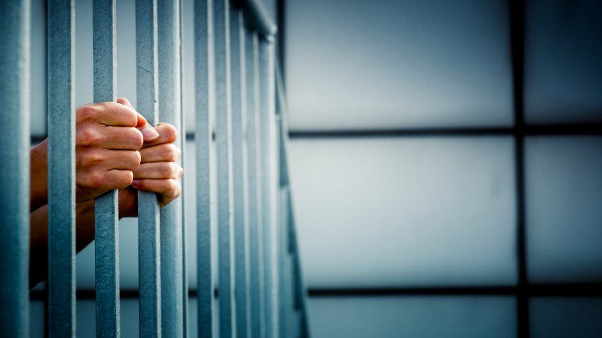 A prisoner behind the jail cell bars .