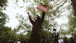 Un manifestante levanta una pancarta en la que se lee «Viva Palestina» en el campus después de que la policía declarara que la manifestación era una concentración ilegal en los terrenos de la Universidad de Virginia el 4 de mayo de 2024 en Charlottesville.