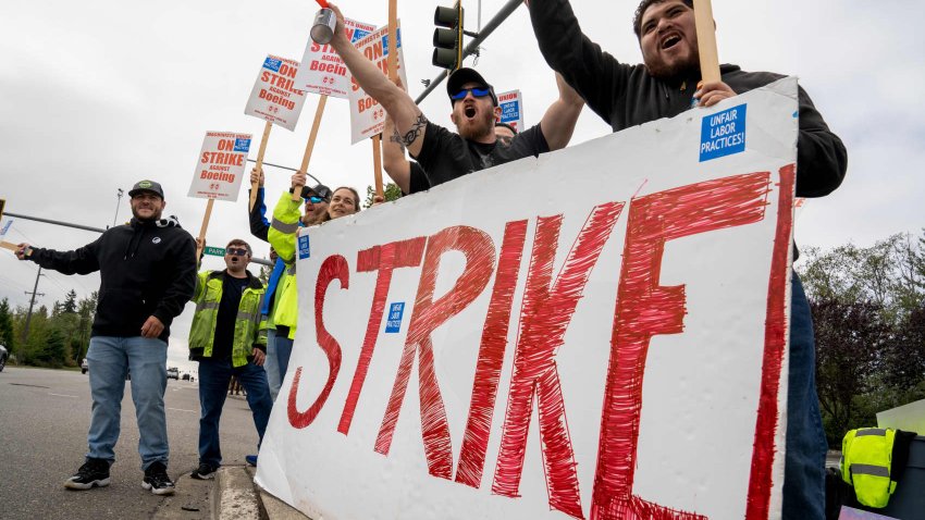 Workers with picket signs outside the Boeing Co. manufacturing facility during a strike in Everett, Washington, US, on Friday, Sept. 13, 2024. 