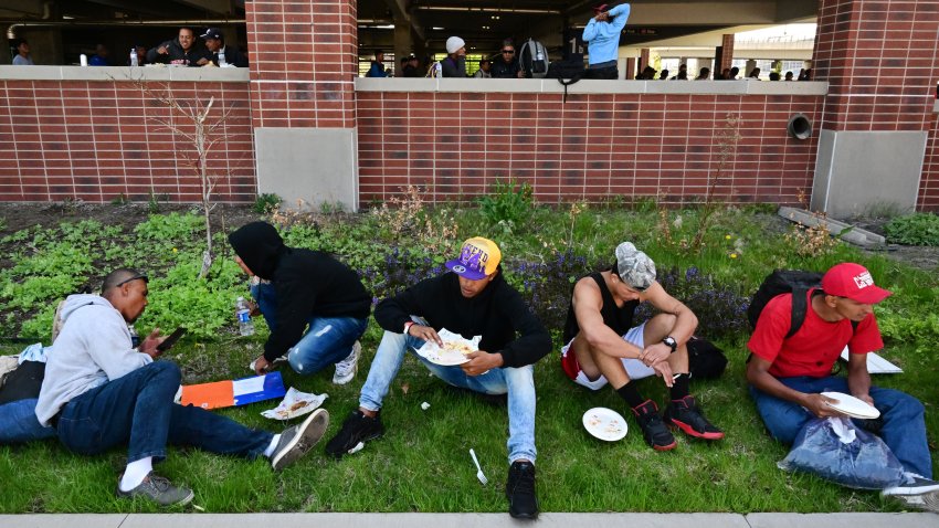 DENVER, CO – MAY 9:  Venezulean migrants eat lunch provided by local food trucks at a migrant processing center on May 9, 2023 in Denver, Colorado. Hundreds of the migrants, primarily from Venezuela, were processed by the city of Denver and directed to shelters and resources as surges of migrants continue to arrive in the US seeking asylum. This comes as Title 42, a policy adopted during the pandemic allowing quick expulsion of many migrants, is set to expire Thursday. They have been walking from Venezuela for months to get to cities like Denver. Many are looking to move to bigger cities like Chicago and New York where some have family but some are looking for place to find work. After being processed, individuals were provided with paper identification to present at shelters for food, clothing and a place to stay. At the request of the city The Denver Post is not releasing the locations of migrant processing or shelters due to security concerns. (Photo by Helen H. Richardson/MediaNews Group/The Denver Post via Getty Images)