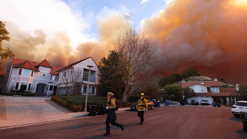 Firefighters run as a brush fire burns in Pacific Palisades, California on January 7, 2025. A fast-moving brushfire in a Los Angeles suburb burned buildings and sparked evacuations Tuesday as “life threatening” winds whipped the region. More than 200 acres (80 hectares) was burning in Pacific Palisades, a upscale spot with multi-million dollar homes in the Santa Monica Mountains, shuttering a key highway and blanketing the area with thick smoke. (Photo by David Swanson / AFP) (Photo by DAVID SWANSON/AFP via Getty Images)