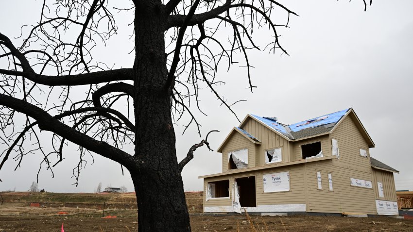 LOUISVILLE, CO – DECEMBER 28: A burned tree still stands near a home that is in the process of being rebuilt in the Coal Creek Ranch neighborhood a year after the Marshall Fire on December 28, 2022 in Louisville, Colorado. Some lots of land where homes once stood are for sale. (Photo by Helen H. Richardson/The Denver Post)